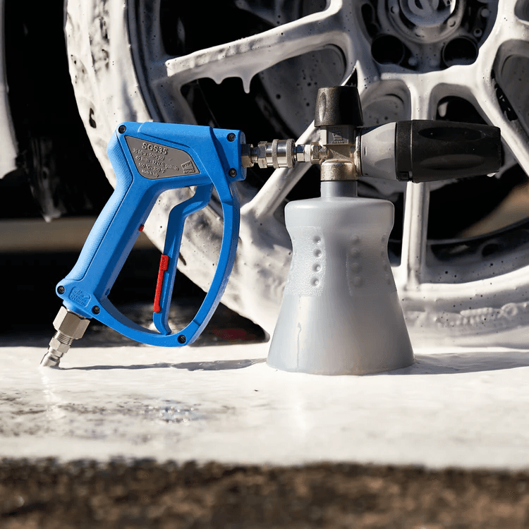Foam cannon attached to a pressure washer producing thick foam on a wheel
