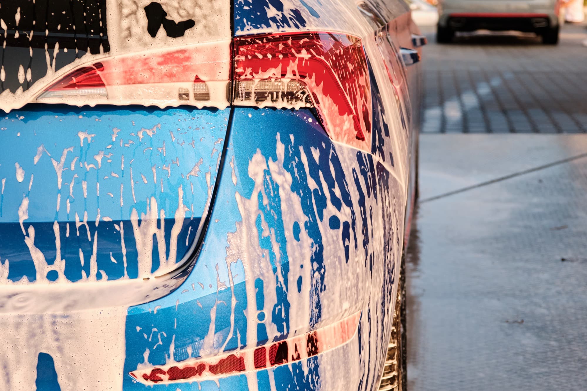 Close-up of soap suds streaming down a car's taillight during a wash